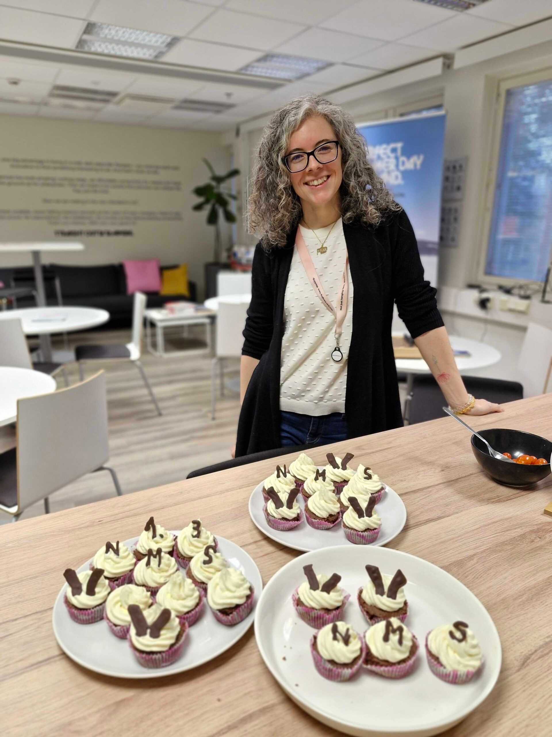 A picture of a Wirepas employee with self-made cupcakes, celebrating a product release