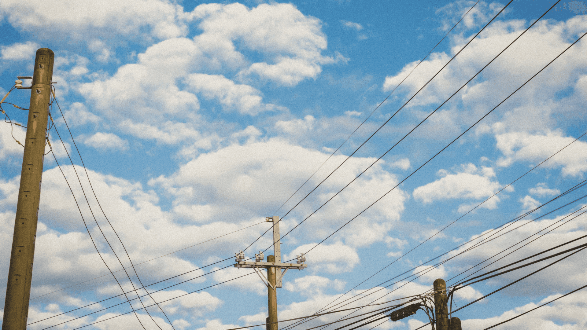 Image of grid transmission network with blue sky and white clouds in the background